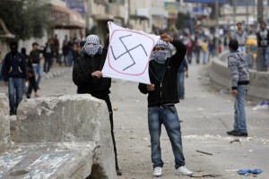Palestinians hold a sign depicting a swastika during clashes at Qalandiya checkpoint